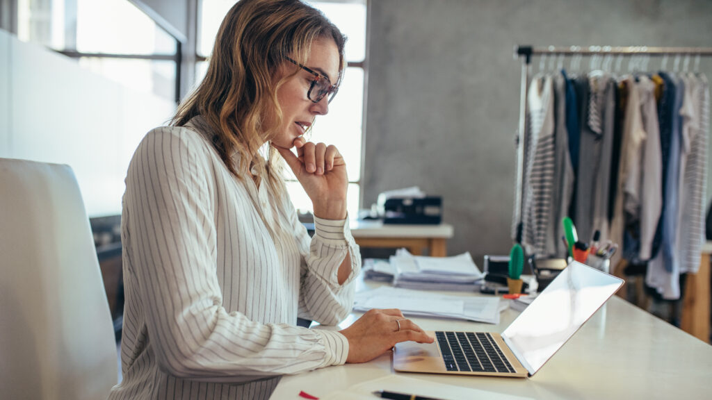 Small business owner planning digital marketing strategies, balancing inbound marketing efforts like SEO and outbound outreach to attract new leads and drive more sales for her eCommerce clothing boutique, with support from Scorpion Five Technologies.