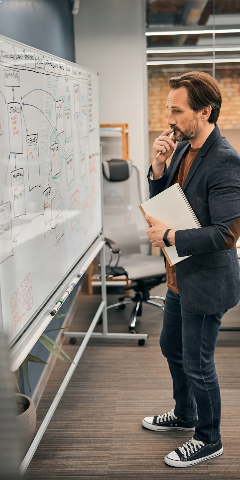 IT strategist evaluating a legacy system flowchart—representing how Scorpion Five Technologies (S5T) approaches modernization through careful planning and phased implementation.