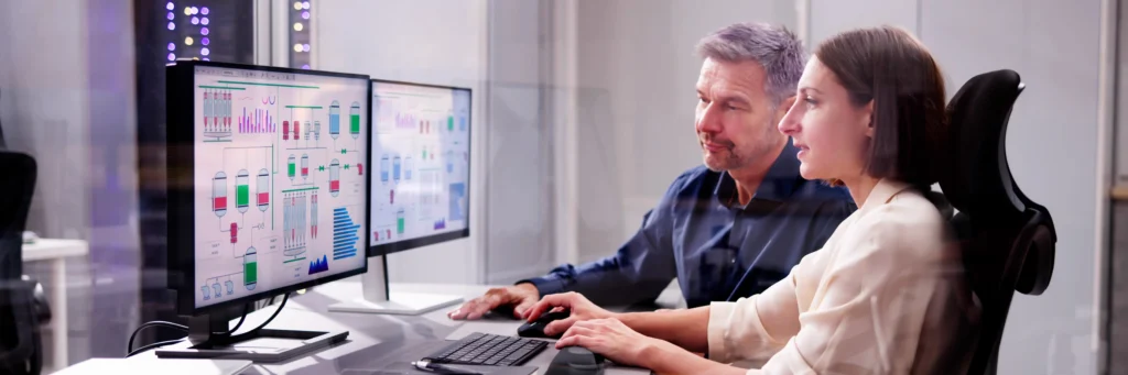 Engineers collaborating on a dual-monitor software interface—representing how Scorpion Five Technologies delivers advanced software solutions for complex, mission-critical operations.