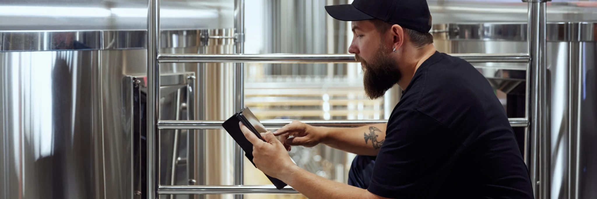 A brewing technologist monitors systems using a tablet, showing how business process automation can provide real time insights.