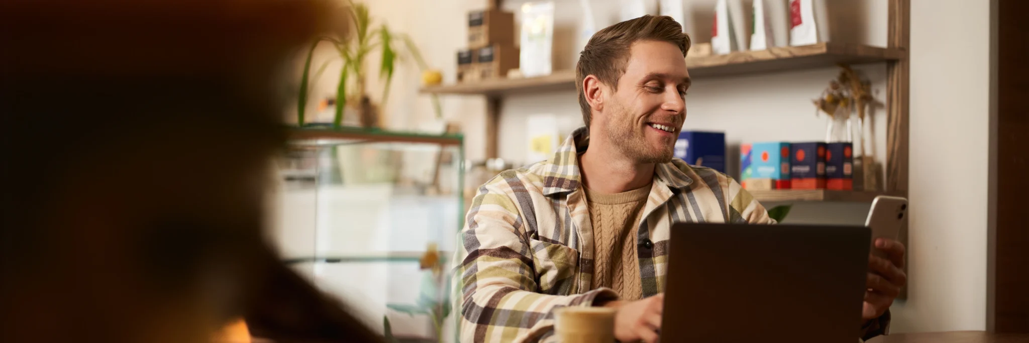 Small business owner reviewing online campaign results on a smartphone while using a laptop—illustrating how Scorpion Five Technologies helps entrepreneurs grow through effective digital marketing strategies.