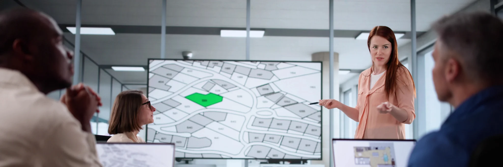GIS professionals reviewing a parcel map on a digital display—representing how Scorpion Five Technologies delivers custom GIS development solutions for spatial analysis, planning, and decision support.
