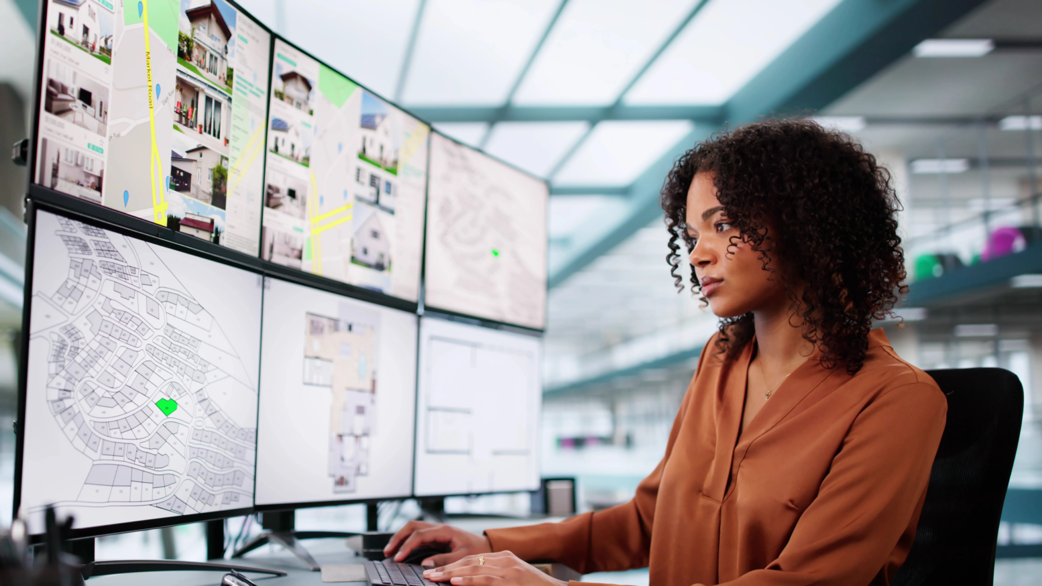 Business professional using a multi-screen custom software interface to manage maps and data through a web application—demonstrating how small business technology enables data-driven insights, improves customer information access, and streamlines decision-making with online tools.