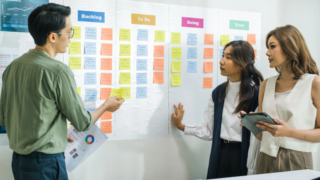 Agile software development team at Scorpion Five Technologies (S5T) collaborating during sprint planning, reviewing a Kanban board with backlog, to-do, doing, and done columns, aligning sprint tasks and priorities for effective execution using agile methodologies.