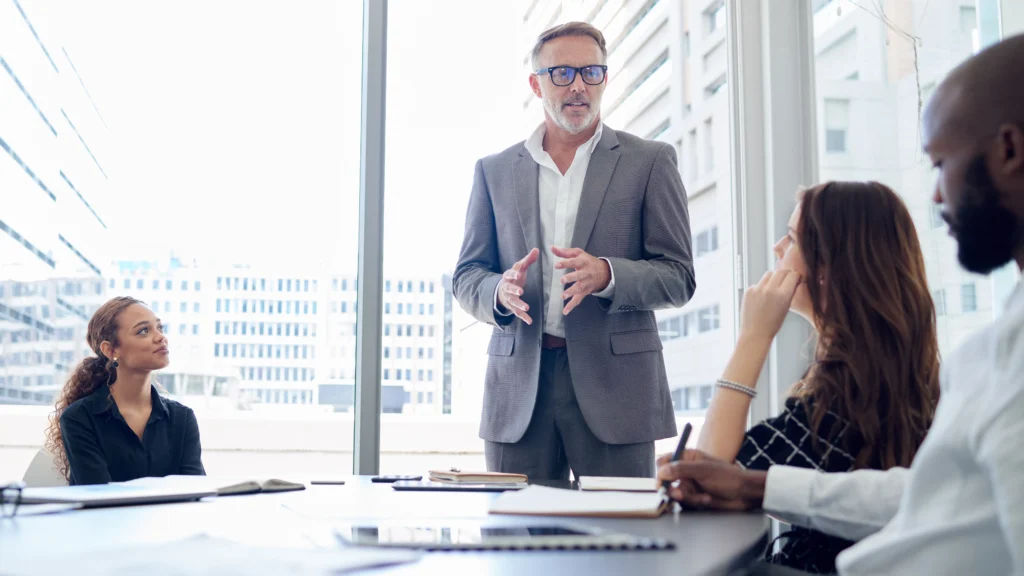 Business leader presenting to cross-functional team in a modern office, representing how Scorpion Five Technologies (S5T) helps large enterprises align teams, streamline operations, and implement scalable enterprise systems for improved efficiency and performance.