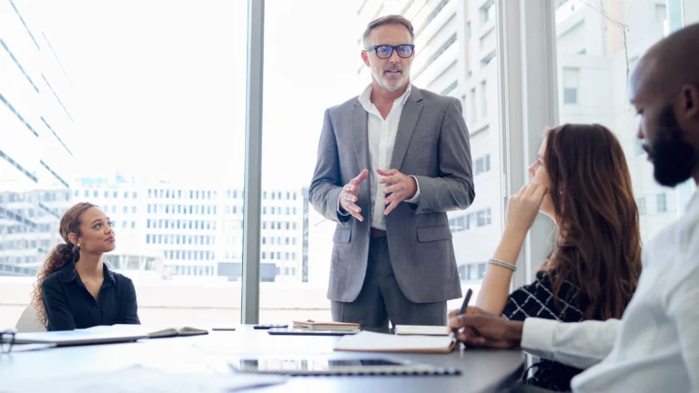 Business leader presenting to cross-functional team in a modern office, representing how Scorpion Five Technologies (S5T) helps large enterprises align teams, streamline operations, and implement scalable enterprise systems for improved efficiency and performance.