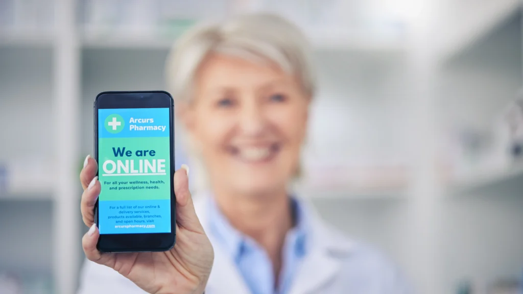 Pharmacist holding a smartphone displaying an online pharmacy message, representing healthcare digital marketing, patient engagement through mobile devices, and compliant digital marketing strategies supported by Scorpion Five Technologies.